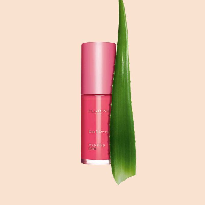 Packshot della nuova tinta labbra rosa di Clarins accanto a una pianta di aloe vera su sfondo bianco
