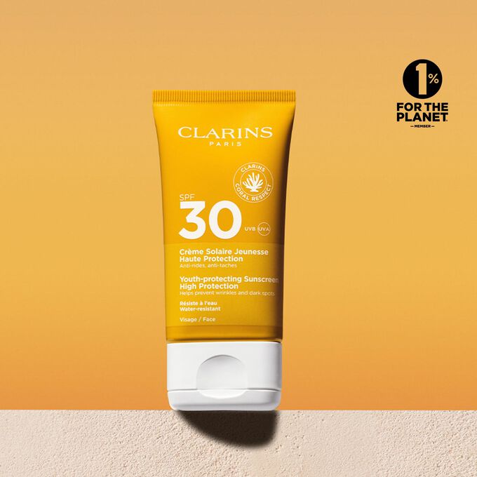 Packshot di un tubetto di crema solare viso fattore 30 con un messaggio che annuncia l’impegno Clarins a tutela dell’ambiente