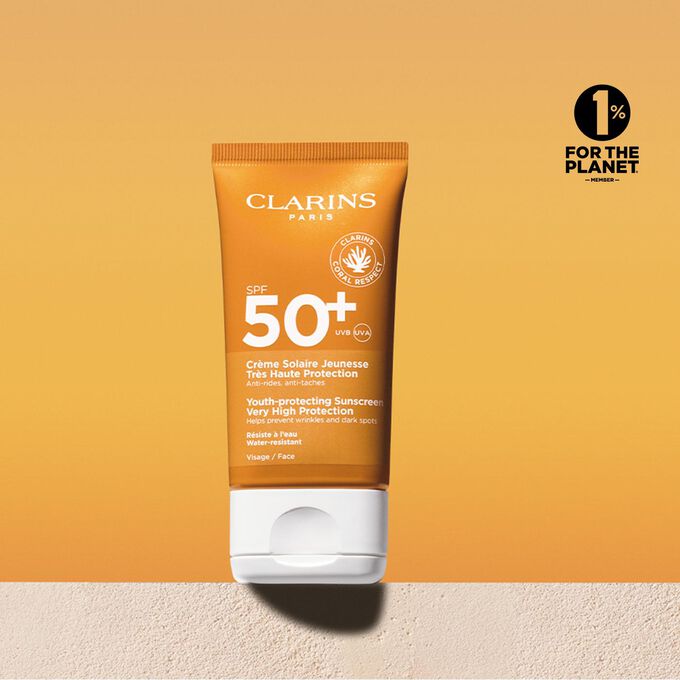 Packshot tubetto di crema solare viso fattore 50 con un messaggio che annuncia l’impegno di Clarins a tutela dell’ambiente